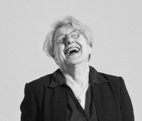 black and white headshot of the artist laughing with her head thrown back