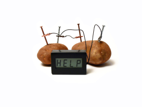 wires run from two potatoes to a digital clock which reads HELP across its screen