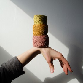 Three spools of yarn sitting on top of a hand