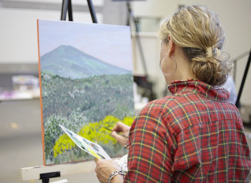 Woman working on a landscape painting