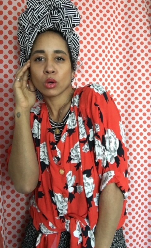 person wearing bold print blouse and hair wrap with polka dot printed backdrop