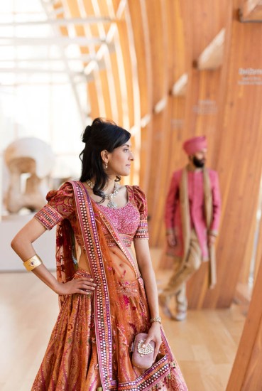 bride wearing sari looking out window in Galleria Italia, groom in background