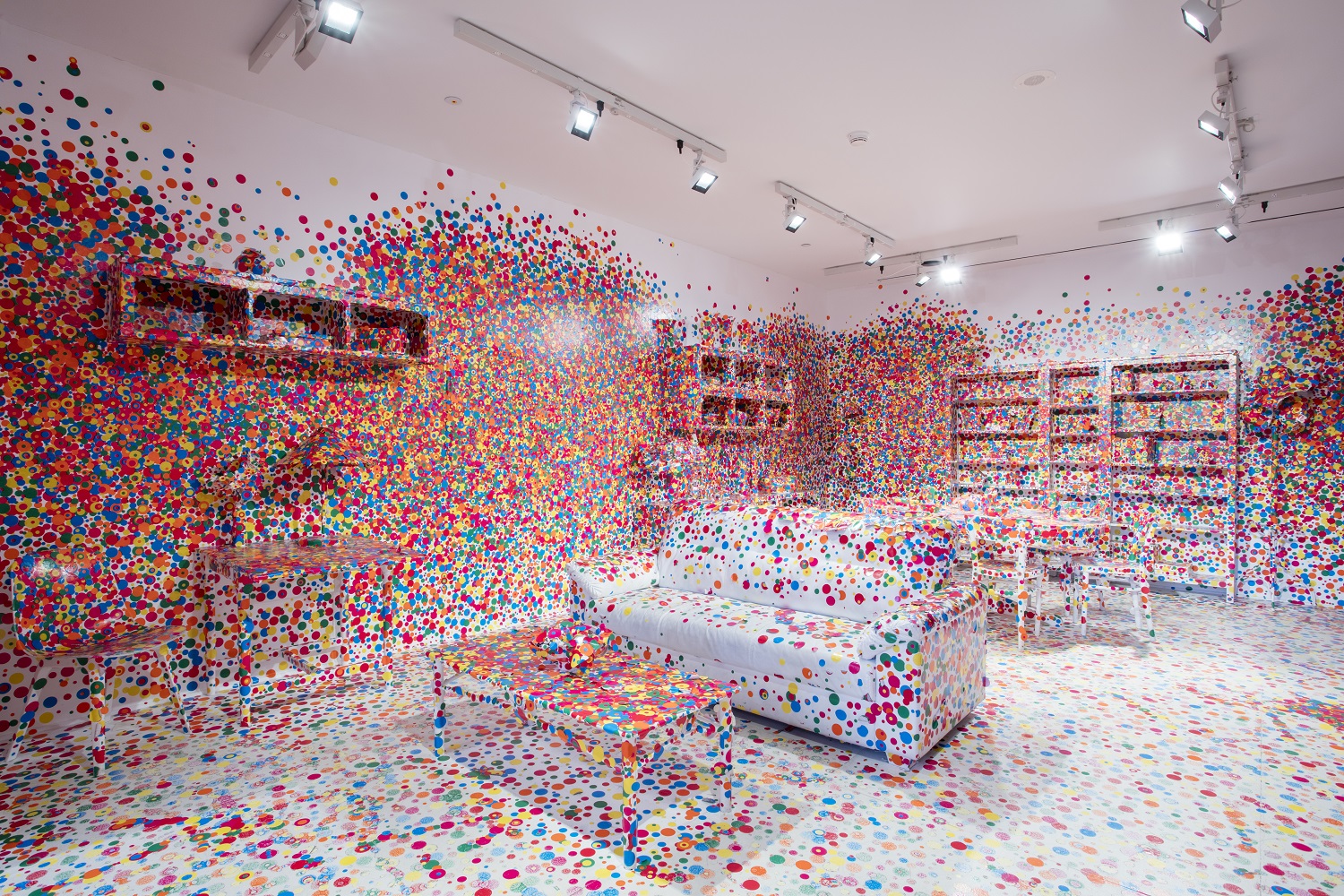 A living room covered in bright polka dots as part of Yayoi Kusama's The Obliteration Room.