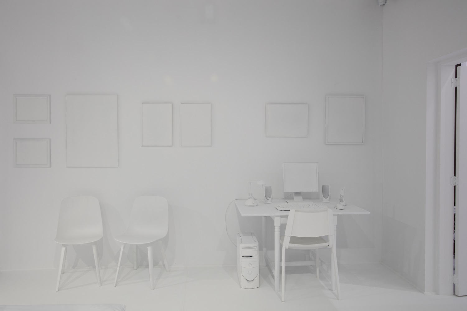 A stark white computer desk and chairs as part of Yayoi Kusama's The Obliteration Room.