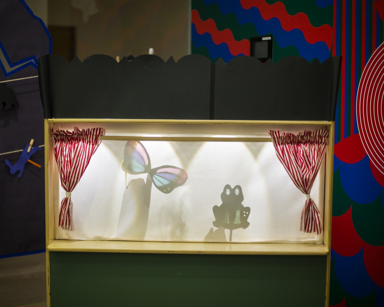A small shadow puppet theatre with a butterfly and frog shadow puppet.
