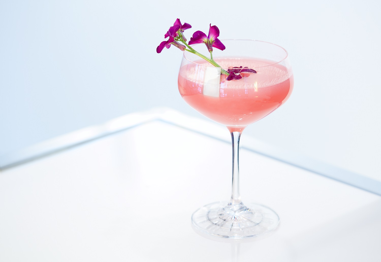 A pink cocktail with a purple flower on top, called "Love Letter for Nixon."