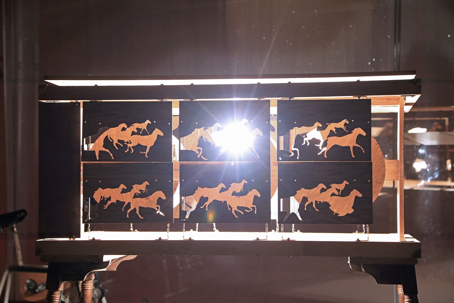 A light shining through cutouts of horses running in Studio F Minus's art installation.