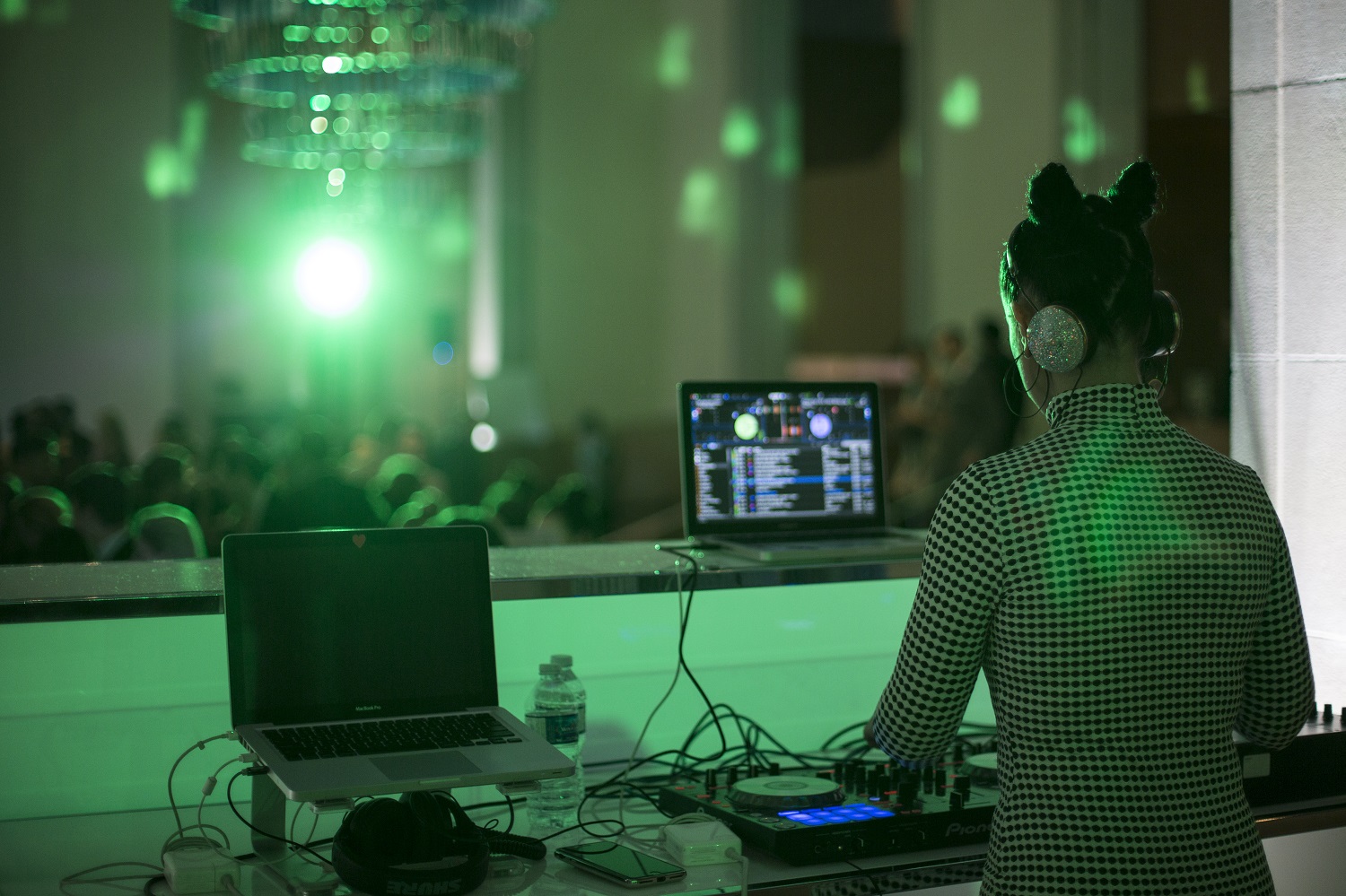 A DJ with her hair in two pigtail buns performs for a large crowd.
