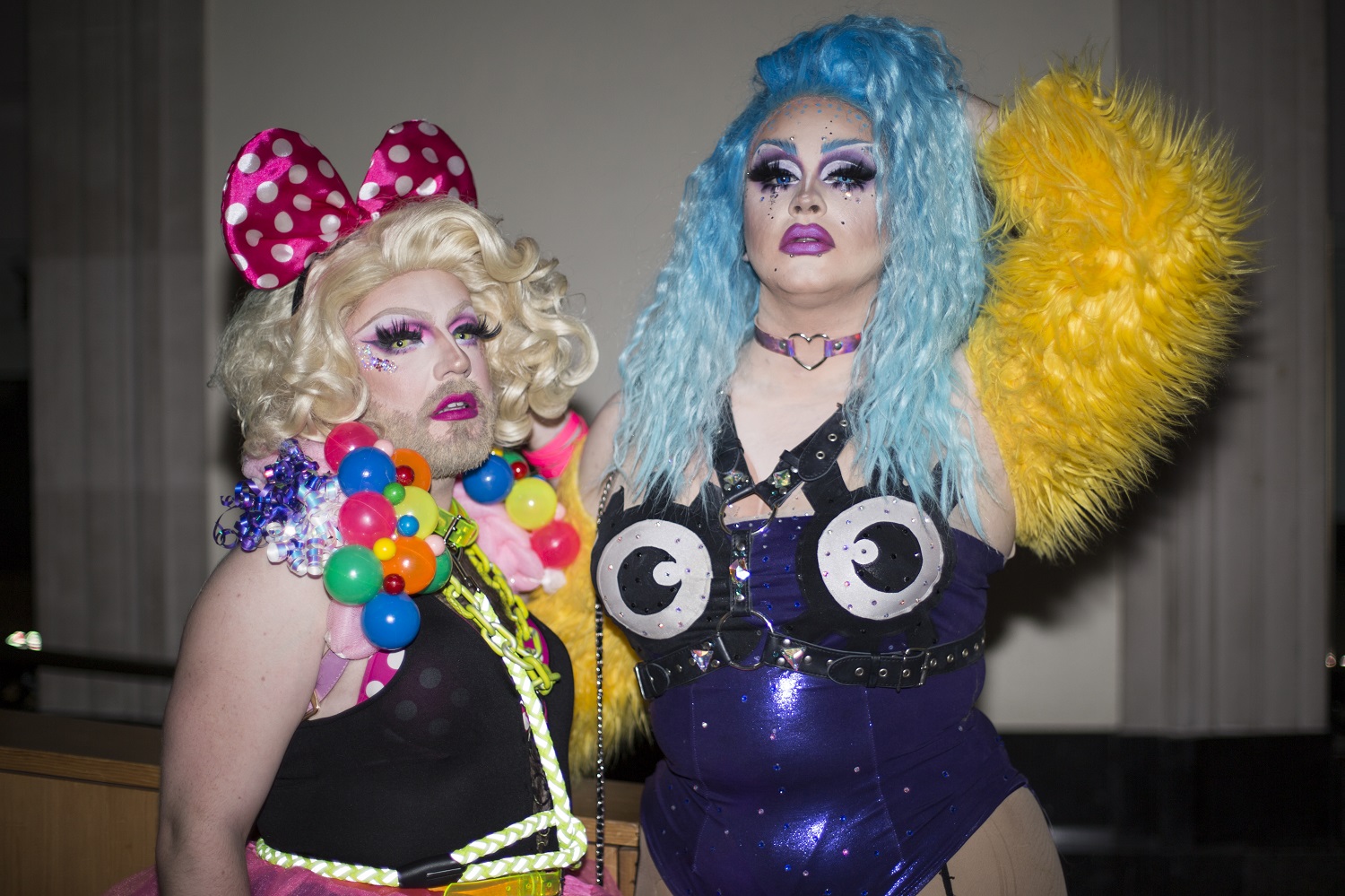 Two drag queens in brightly coloured bodysuits and wigs.