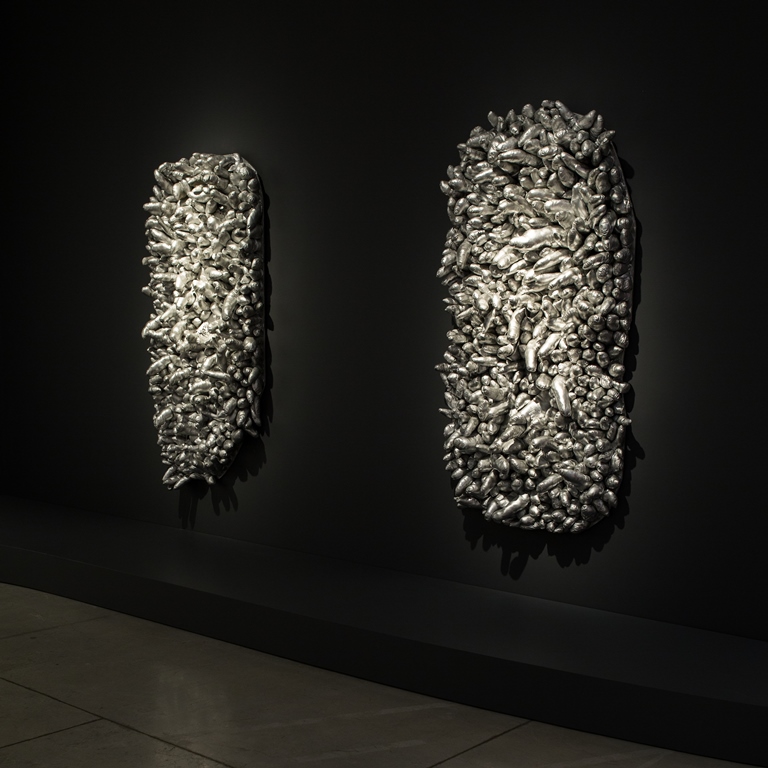 Two silver sculptures by Kusama hung on a wall