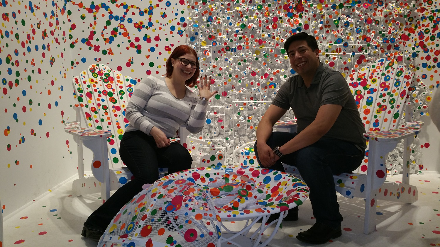 A woman shows off her engagement ring beside her fiance in Yayoi Kusamas Obliteration Room.