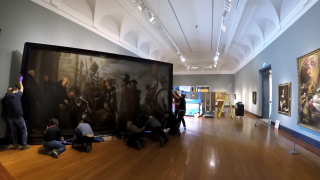 A large painting being moved from a wall in the AGO