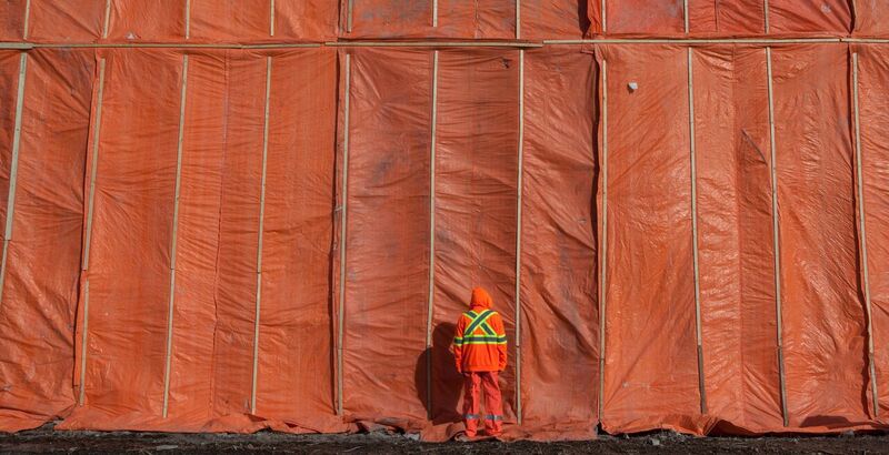 Rebecca Belmore's artist (no. 2), a photo of a man in orange clothes in front of an orange wall
