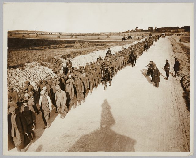 Prisoners walking while being supervised by soldiers