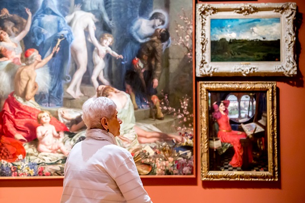 A senior looking at paintings