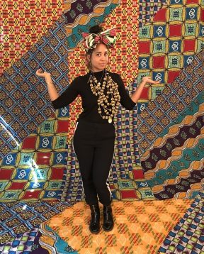 A woman posing in front of fabrics
