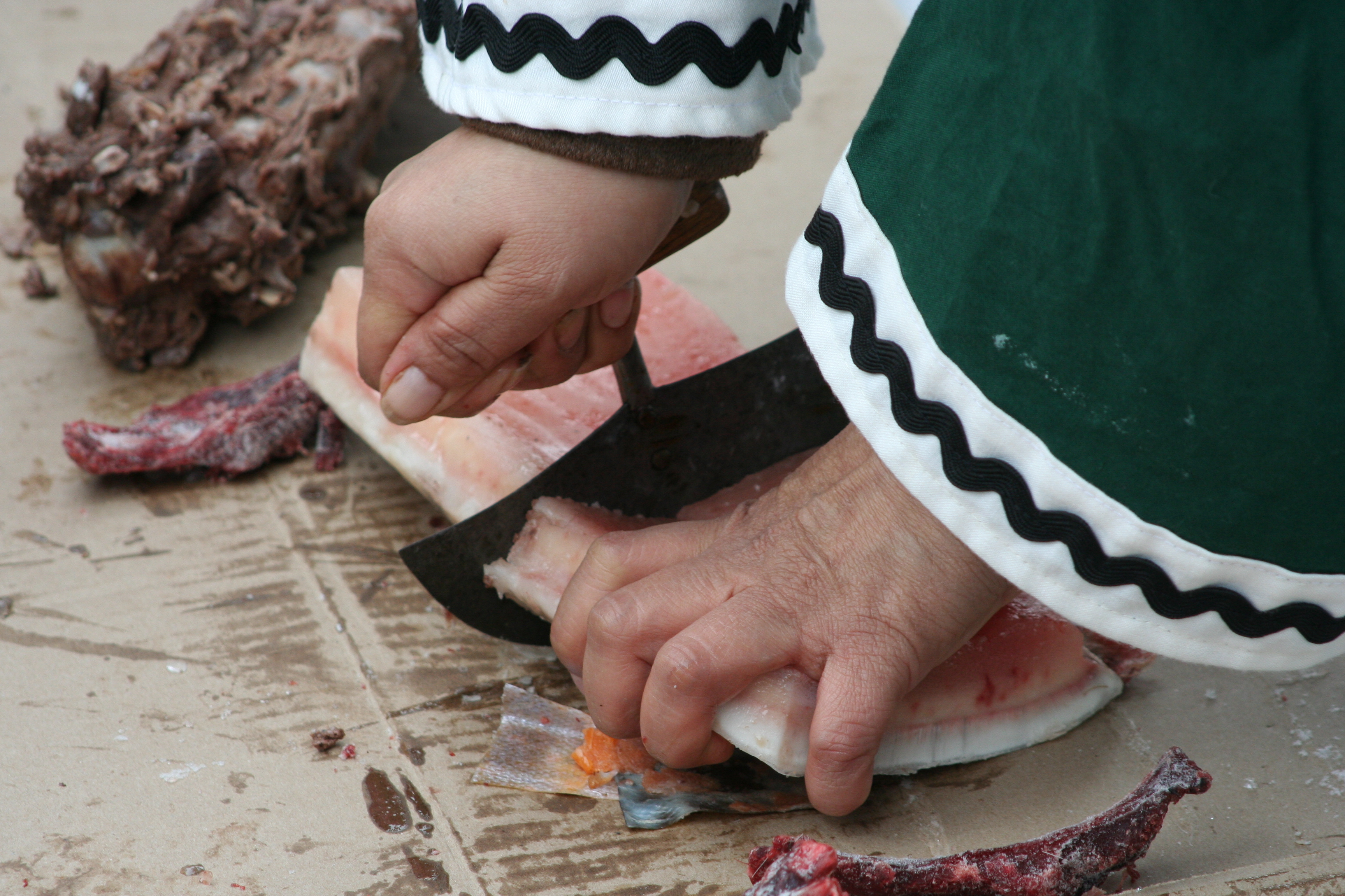 Photograph of hands slicing pieces of whale fat 