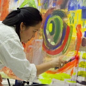 Woman working on large abstract painting