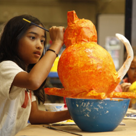 child painting papier mache sculpture