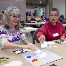 Two women paint using a new technique during the AGO Seniors Social
