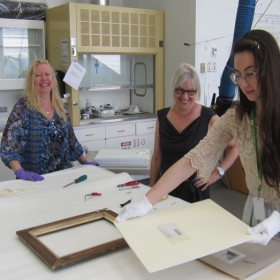 Sabine Schaefer, Art Handler, delivers works on paper to Maureen Del Degan, Collections Care Specialist and Elizabeth Carroll (handling matted work of art using cotton gloves)