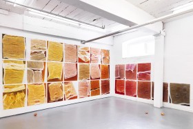 Image of 35 photo works in red and yellow tones on a white wall
