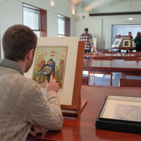 Person in study room looking at print on easel