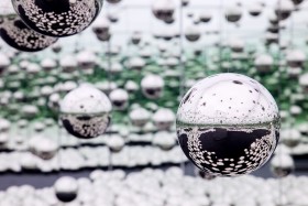 A number of floating reflective balls. Those in the foreground in focus and balls in the background are blurred.