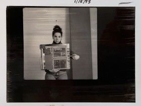 black and white photograph of Elizabeth Greenberg in a test shot, holding a document and pointing to it