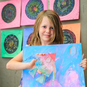child holding colourful artwork during rainbow adventures camp