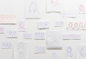 Installation view of figure drawings taped to wall