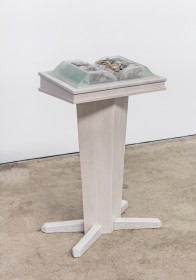 Free standing sculpture of podium, atop of which is book whose pages are rocks