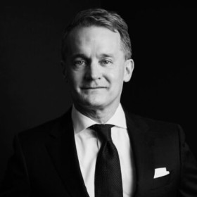 A black and white photo of Seamus O'Regan, wearing a suit, looking directly at the viewer