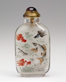 This image shows a traditional Chinese glass snuff bottle, featuring hand-painted artwork which depicts colorful fish swimming among plants, with orange-red goldfish and other fish in shades of gray and black. The top of the bottle is made of metal, with a purple gemstone as a stopper.  