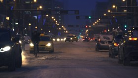 Still image of Edmonton at night in the snow with a single cyclist with cars