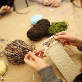 persons hands weaving yarn