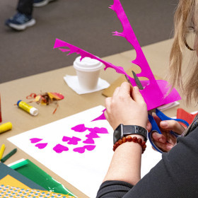 Woman cutting bright pink paper.