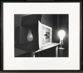 Black and white image of a pinhole camera, lightbulb illuminated