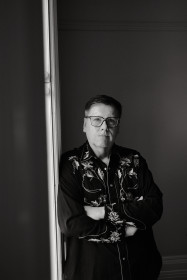 Black and white photo of a man leaning against a wall