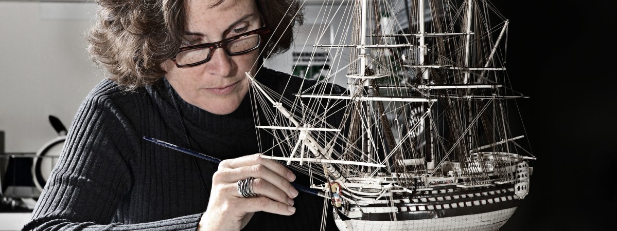 conservator working on ship model