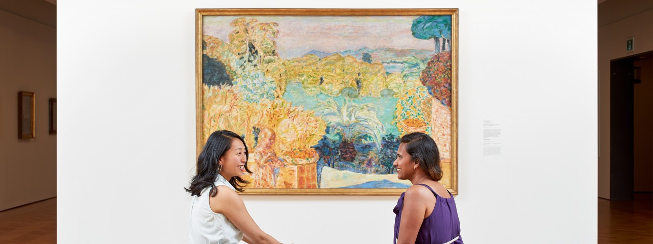two people sitting in front of a painting