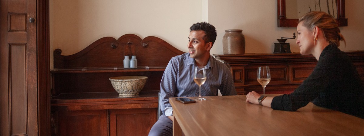 woman and man sitting by the table having conversation over a glass of wine