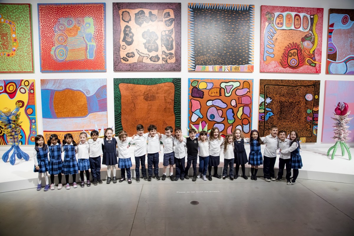 A group of schoolchildren in front of works by Yayoi Kusama