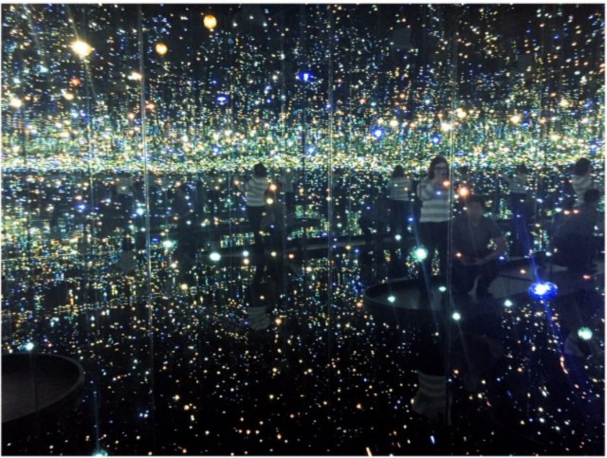 A man proposes on one knee to his girlfriend inside Yayoi Kusama's Infinity Mirror Room.