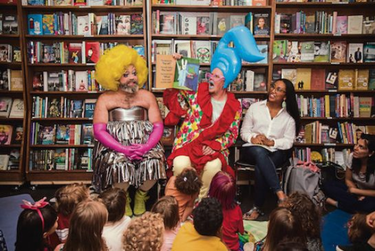 Two men in costume read a book to a group of children