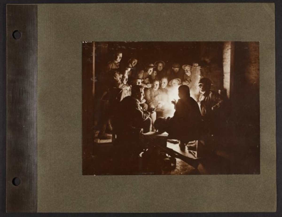 A photo album page of soldiers sitting around a fire