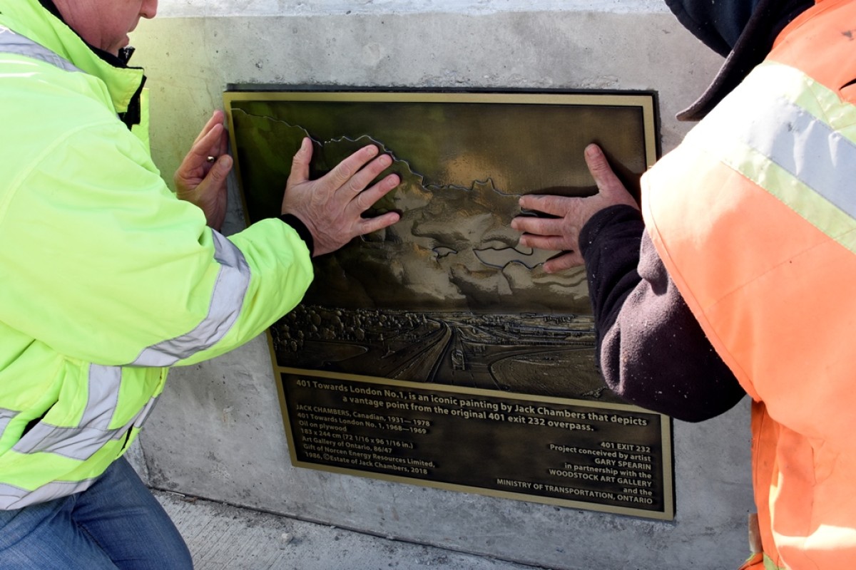 Two people adding a plaque to a bridge