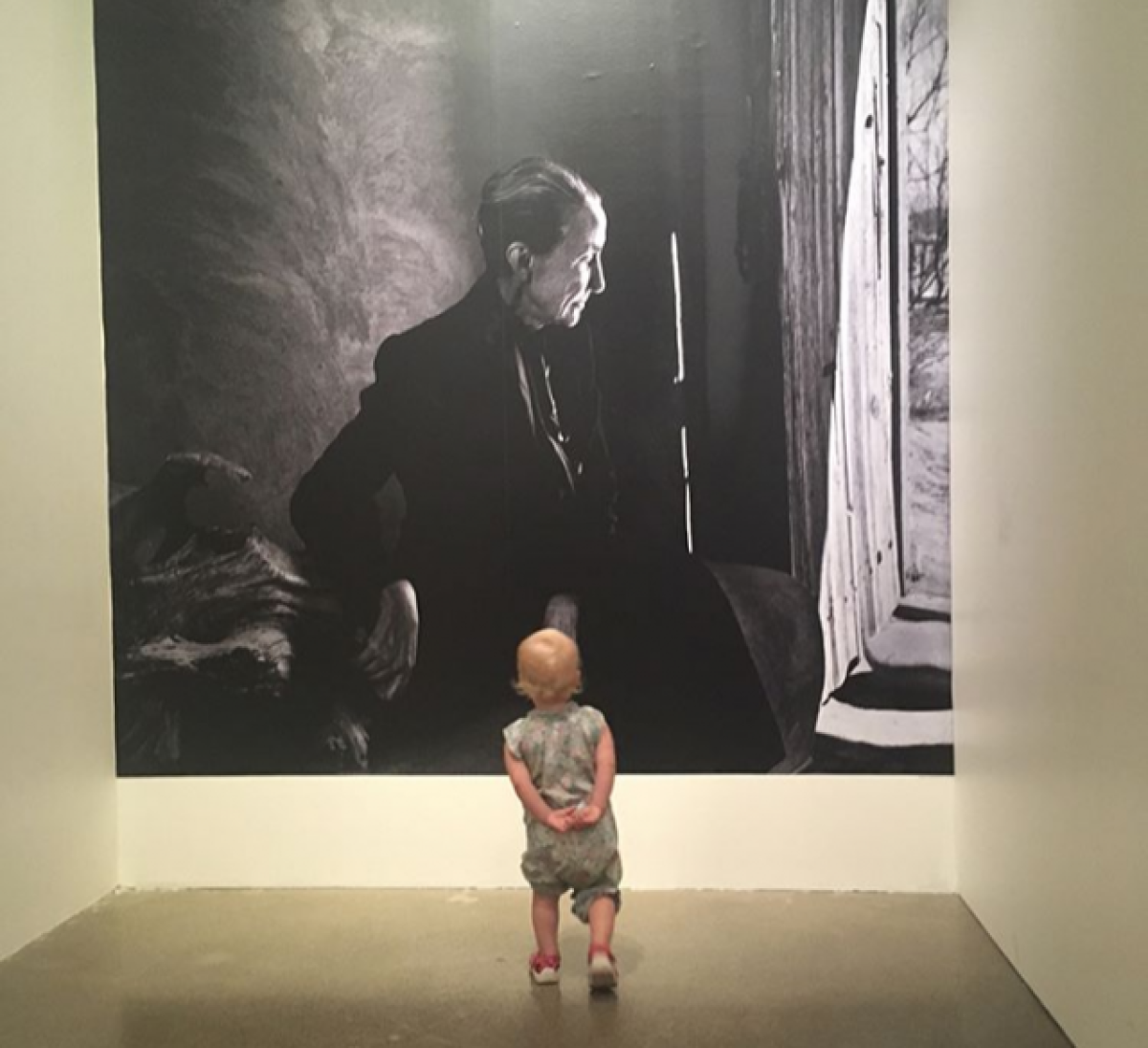 A toddler looking at a mural of Georgia O'Keeffe