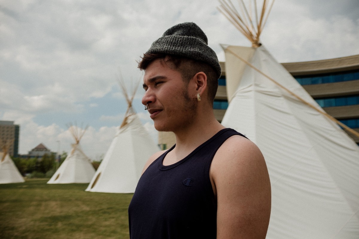 Book Cover and Writer Billy-Ray Belcourt outdoors with three white tipis behind him. 