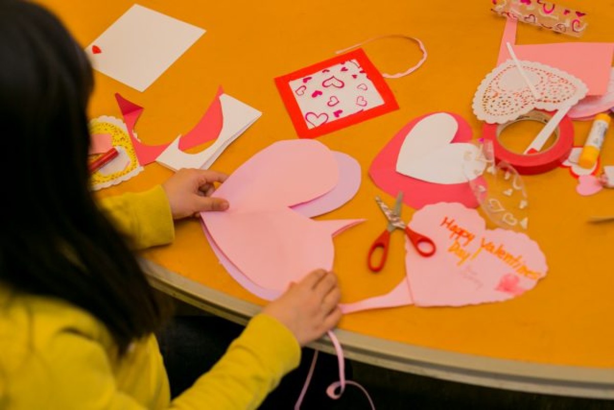 Kid making hearts out of construction paper